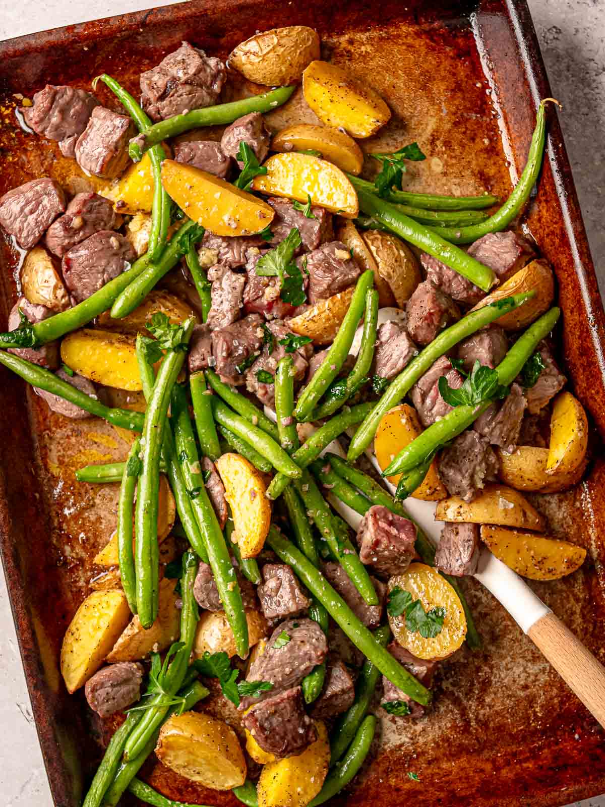Tender sirloin steak bites, golden potatoes, and crisp green beans roasted on a sheet pan.