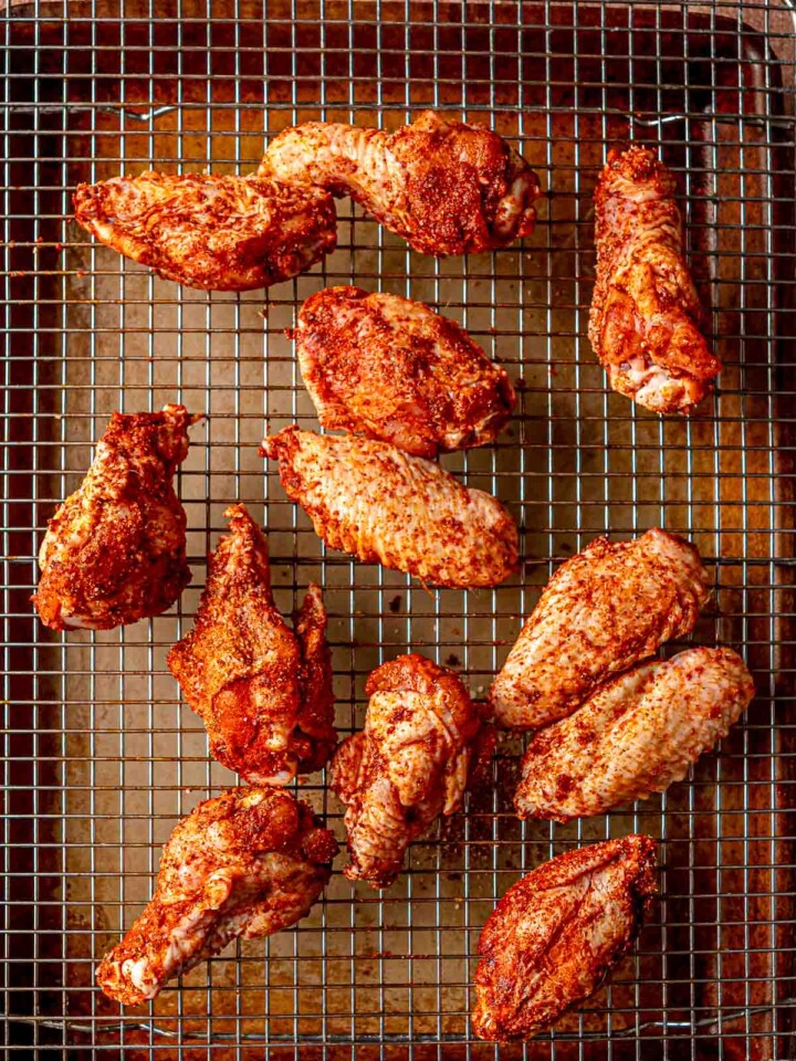 Seasoned chicken wings arranged on a wire rack set over a baking sheet.