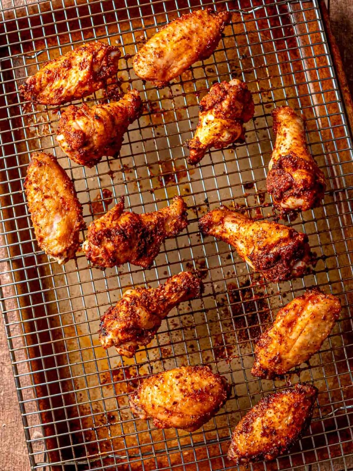 Chicken wings baking on a wire rack as the seasoning crisps in the oven.