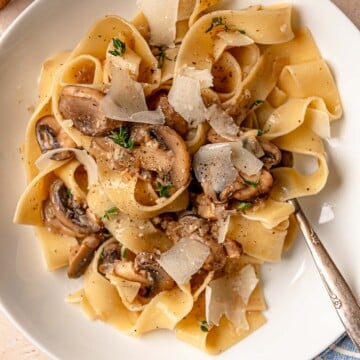 Creamy mushroom pasta plated with Parmesan shavings and cracked black pepper.