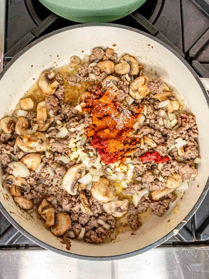 Garlic, tomato paste, paprika, salt, and pepper added to the beef and mushroom mixture.