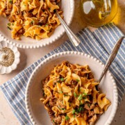 Ground beef stroganoff served in a bowl with egg noodles and fresh parsley.