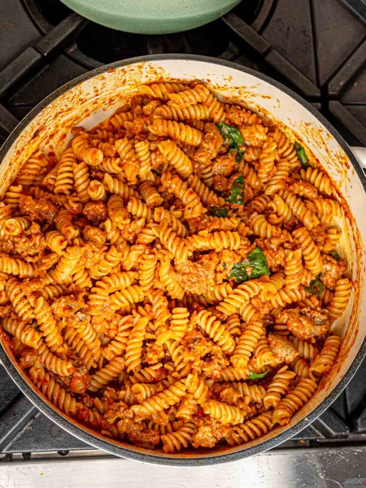 Roasted red pepper pasta with sausage finished with fresh basil.