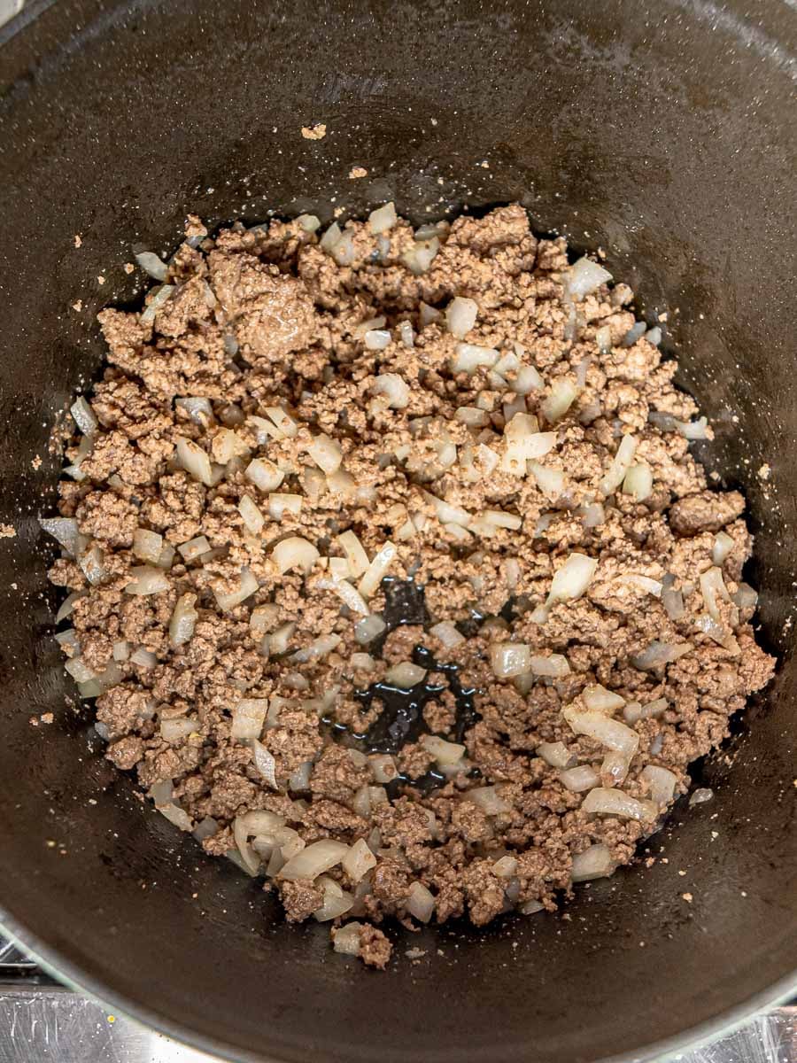 Ground beef and diced onions cooking together in a skillet.