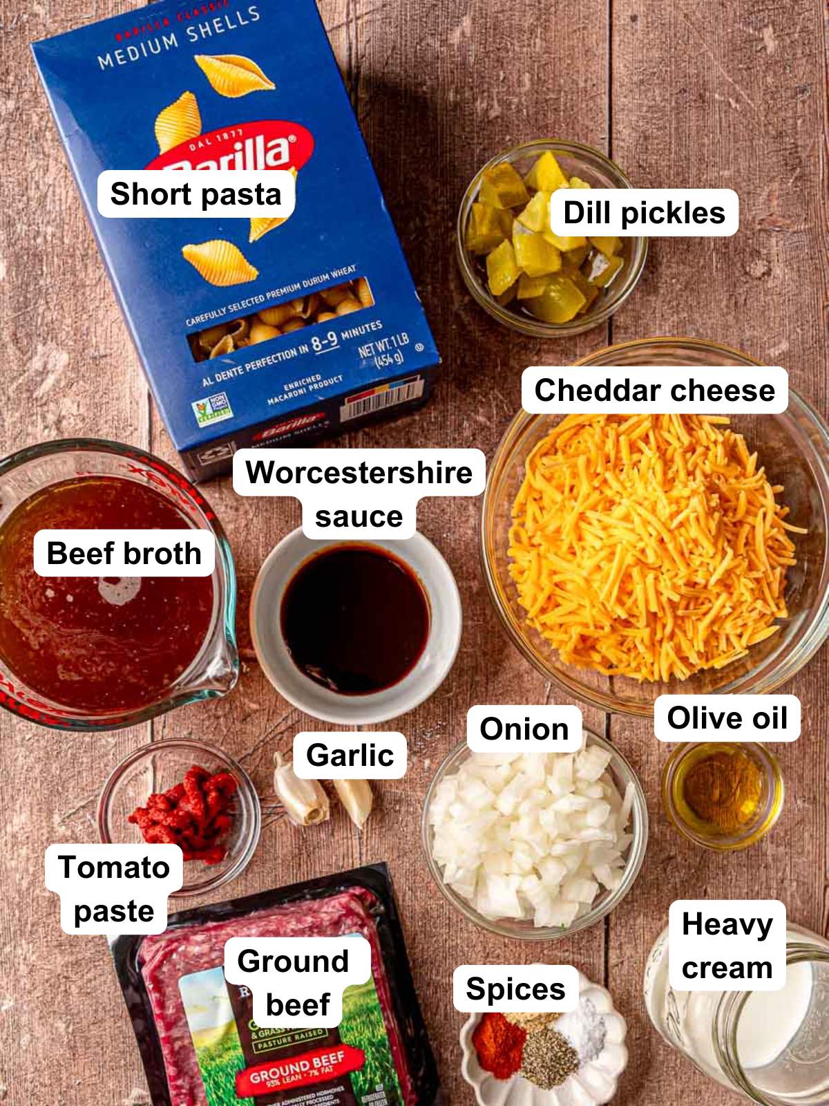 Ingredients for cheeseburger pasta arranged on a wooden board.
