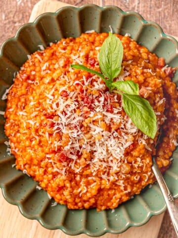 Tomato pastina with guanciale in a green scalloped-edge bowl.