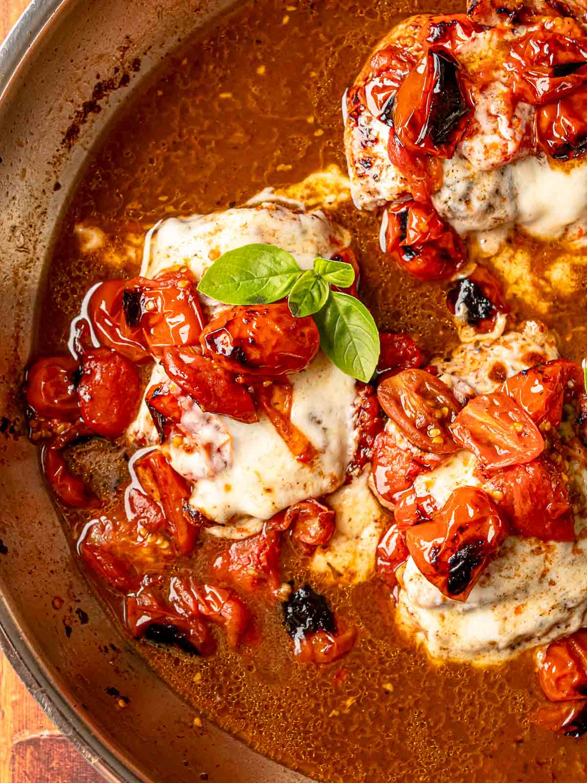 Caprese chicken with bubbling mozzarella, caramelized cherry tomatoes, and basil in balsamic pan sauce.