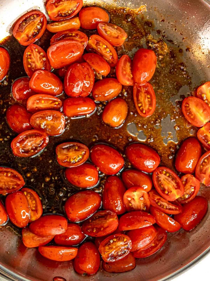 Cherry tomatoes softening and releasing juices in balsamic pan sauce.