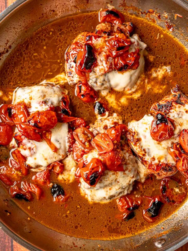 Melted mozzarella covering chicken thighs with caramelized tomatoes in balsamic glaze.