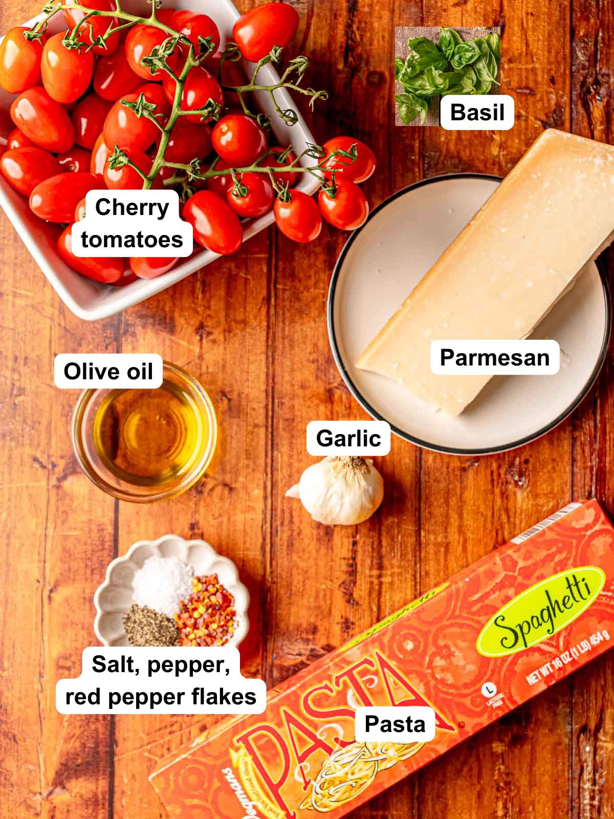 Ingredients for cherry tomato pasta: tomatoes on vine, olive oil, garlic, Parmesan wedge, basil, spaghetti box, salt, pepper, red pepper flakes.