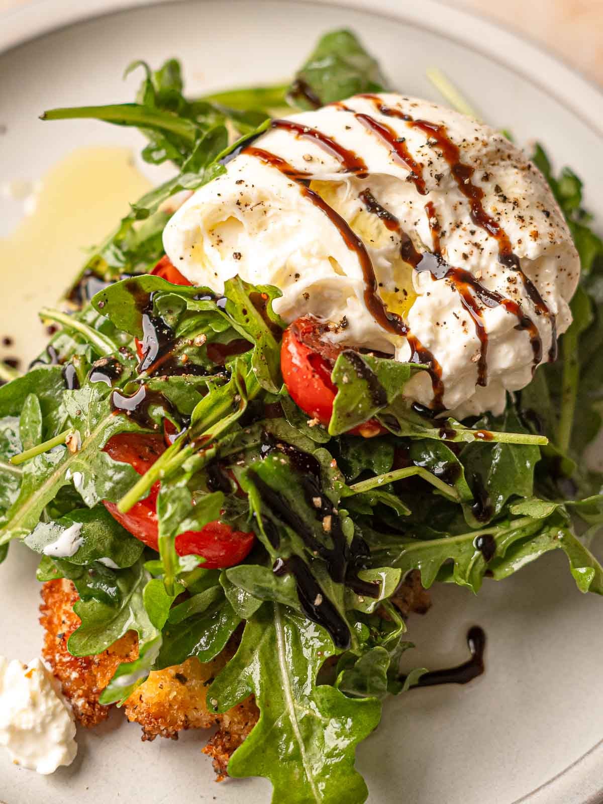 Burrata with balsamic glaze drizzled over arugula salad on crispy chicken milanese cutlet.