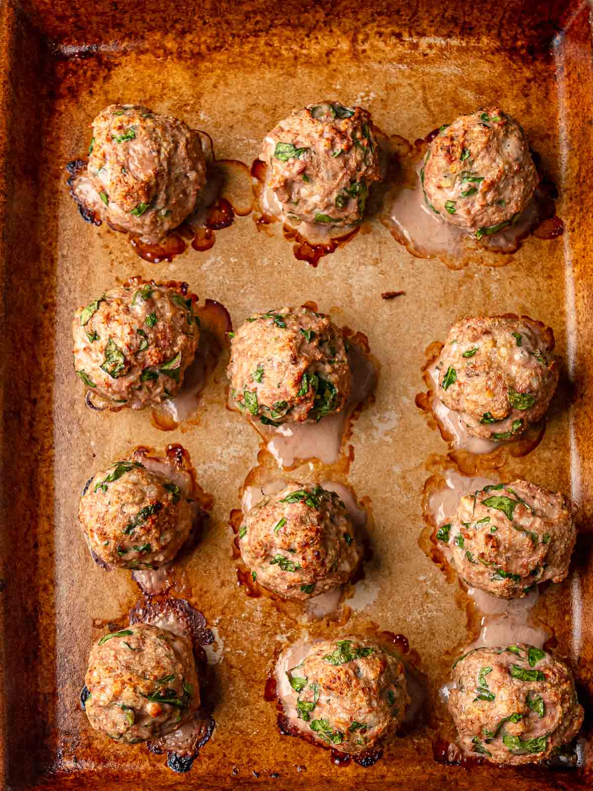 Baked turkey spinach meatballs with golden-brown exterior on baking sheet.