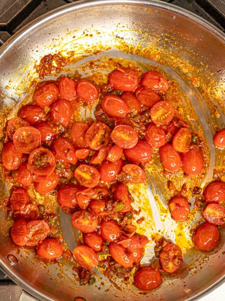 Cherry tomatoes cooking with tomato paste, shallots, and pepper.