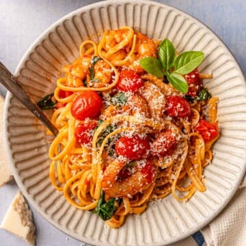 Spicy tomato shrimp pasta served in bowls with Parmesan, basil, and olive oil.