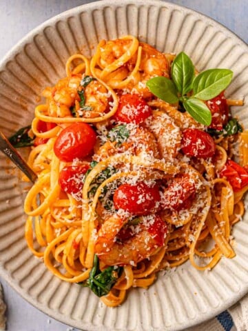 Spicy tomato shrimp pasta served in bowls with Parmesan, basil, and olive oil.