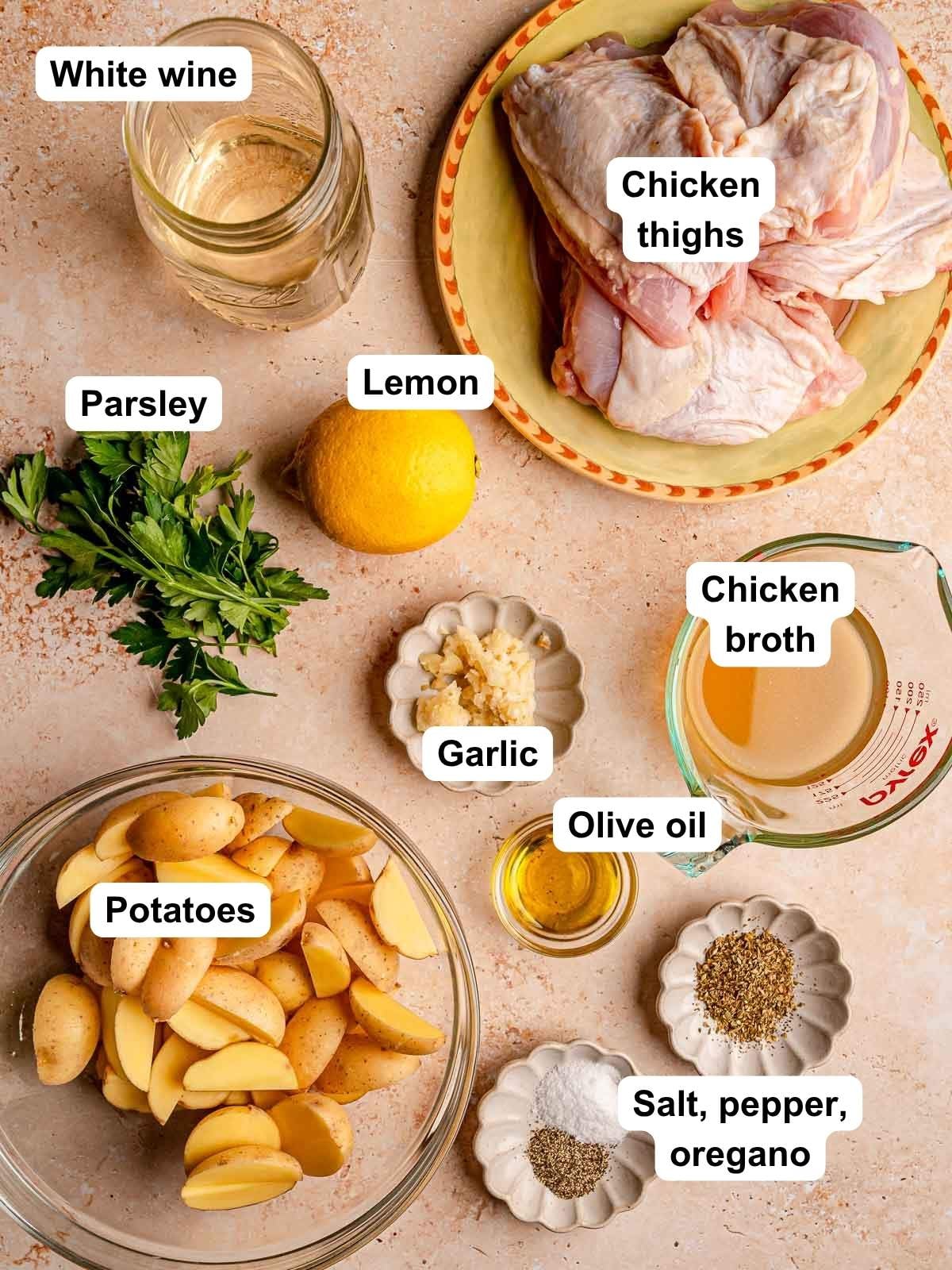 Ingredients for baked lemon chicken and potatoes include chicken thighs, baby potatoes, lemon, garlic, parsley, white wine, chicken broth, olive oil, and seasonings.