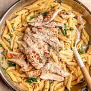 Overhead view of creamy garlic Parmesan chicken pasta with penne, spinach, sliced chicken, red pepper flakes and grated Parmesan.