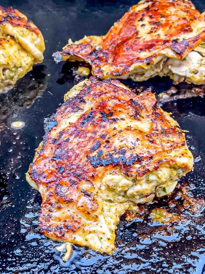 Herb-marinated chicken thighs cooking on a hot griddle until golden and charred.