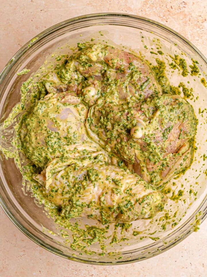 Bone-in chicken thighs evenly coated in a creamy fresh herb marinade.