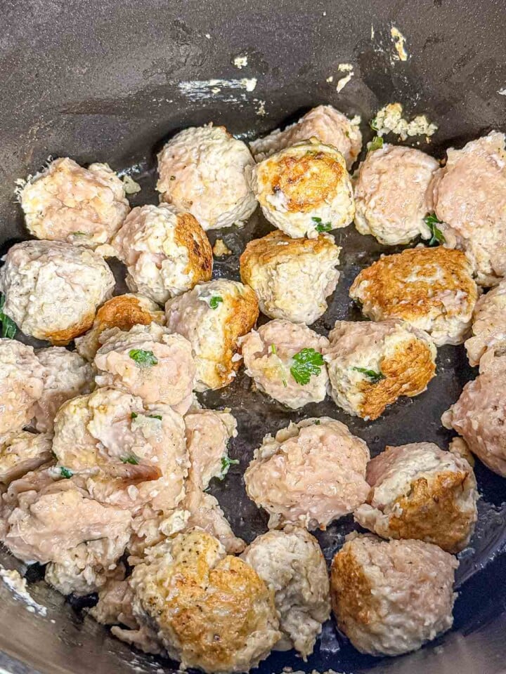 Chicken meatballs are browned in a large pot until golden on the outside before being added to the soup.