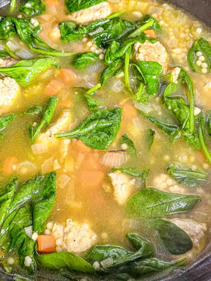Fresh spinach and acini di pepe cook with chicken meatballs, carrots, celery, and onion in Italian wedding soup.