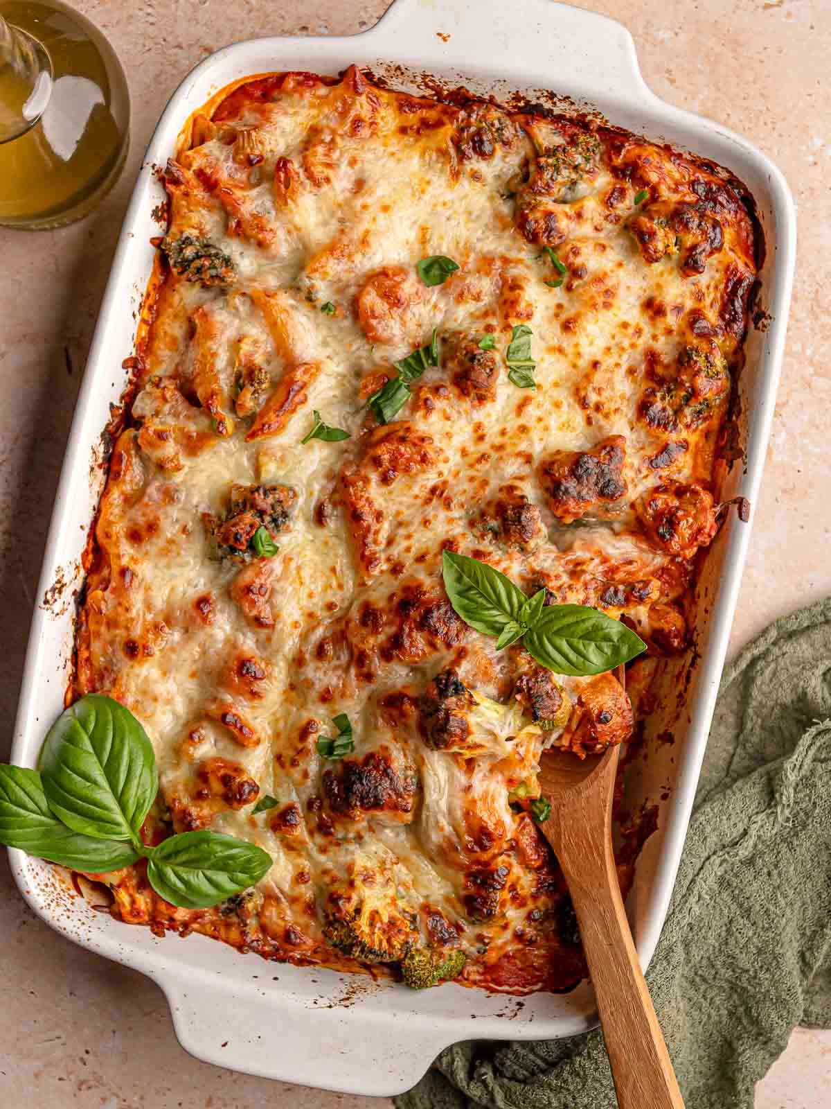 No-boil pasta bake with penne, tomato sauce, broccoli, sausage and melted mozzarella, garnished with fresh basil.