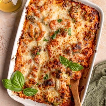 Cheesy no-boil pasta bake with penne, sausage and broccoli in tomato sauce, topped with fresh basil.