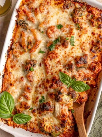 Cheesy no-boil pasta bake with penne, sausage and broccoli in tomato sauce, topped with fresh basil.