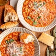 Bowls of thick pasta e fagioli are topped with freshly grated Parmesan and parsley and served alongside crusty bread.
