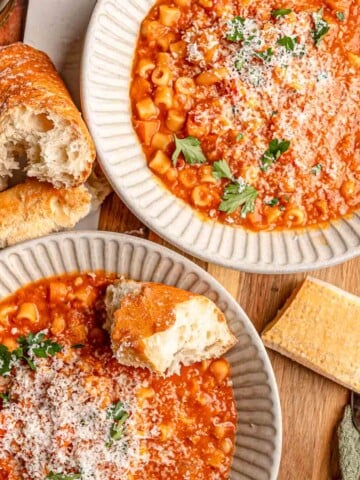 Bowls of thick pasta e fagioli are topped with freshly grated Parmesan and parsley and served alongside crusty bread.