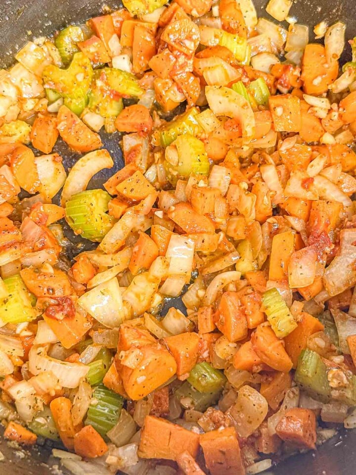 Carrots, celery, onion, garlic, and tomato paste cook together until the vegetables are softened and coated in tomato.