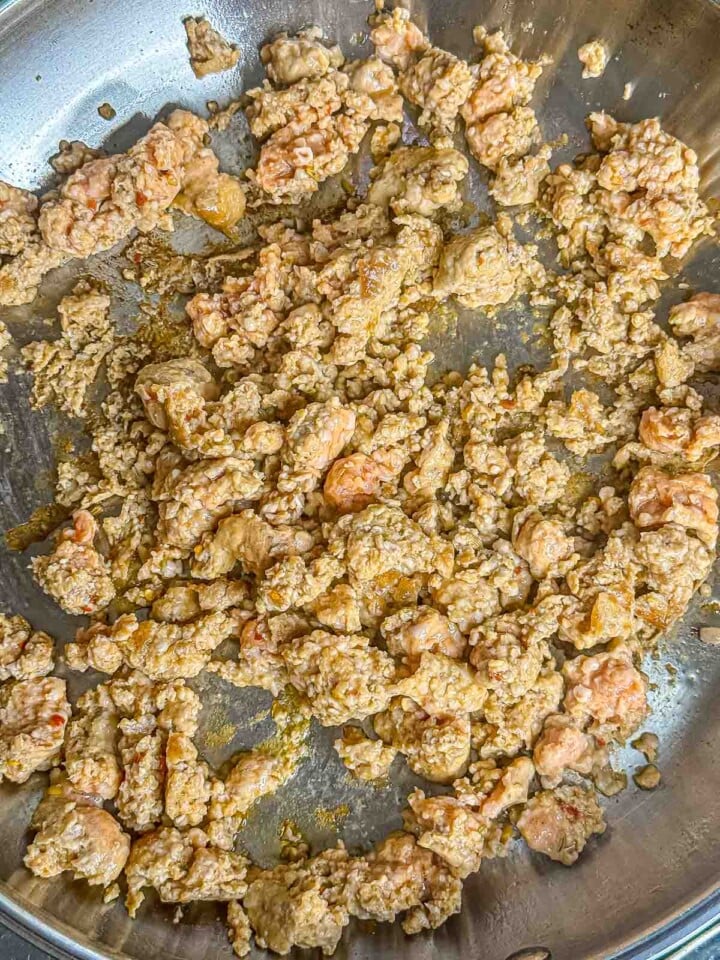 Crumbled Italian sausage browning in a large skillet.