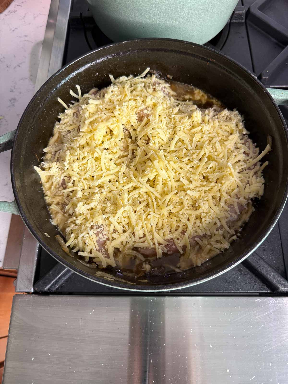 Chicken breasts and caramelized onions topped with shredded Gruyère cheese before baking.