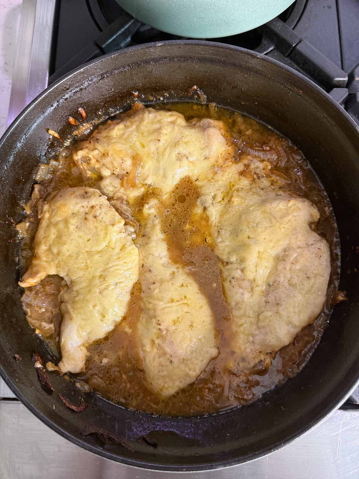French onion chicken bake with melted Gruyère cheese and caramelized onion sauce in a skillet.