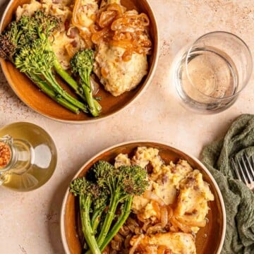 Two plates of French onion chicken bake served with mashed potatoes and broccolini.