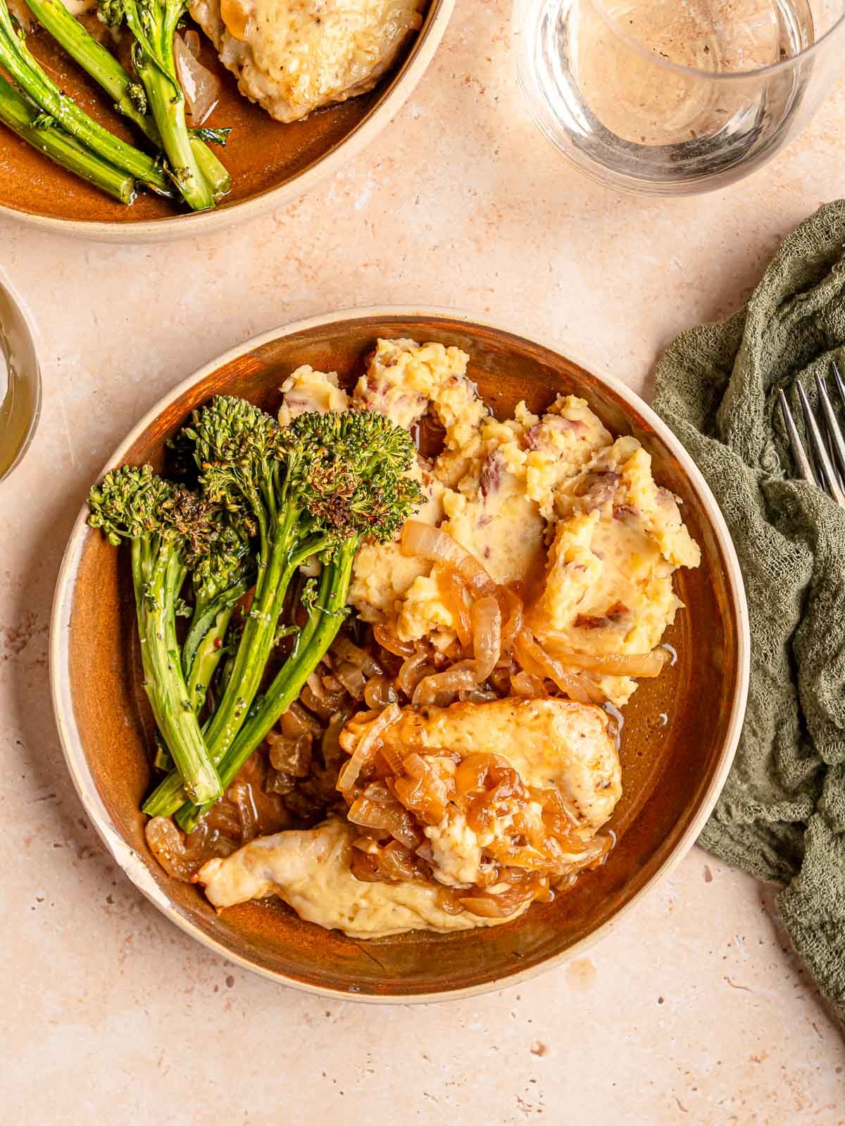 Overhead view of French onion chicken with caramelized onion sauce, mashed potatoes, and broccolini.