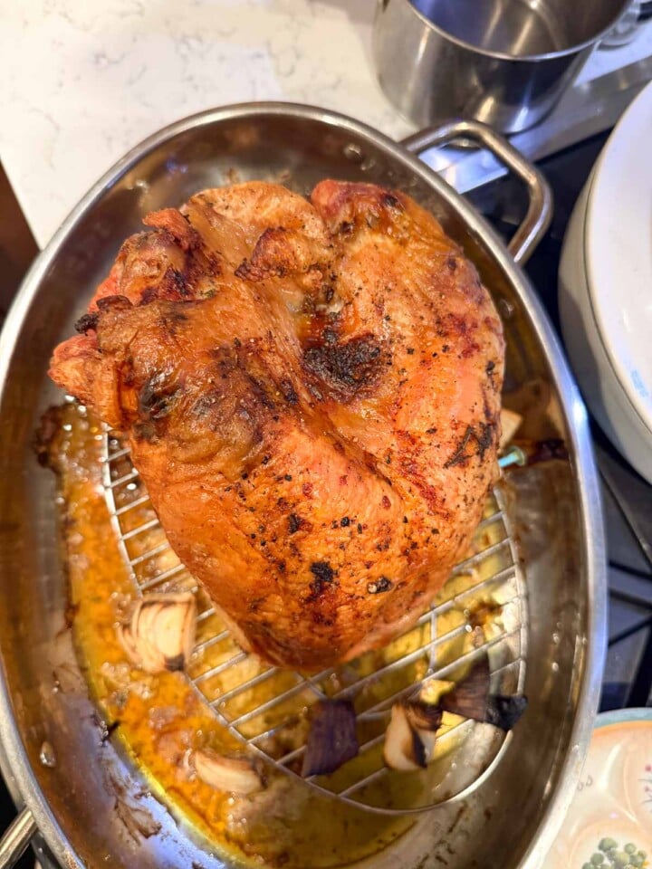 Golden roasted turkey breast on a rack above onions and pan juices.